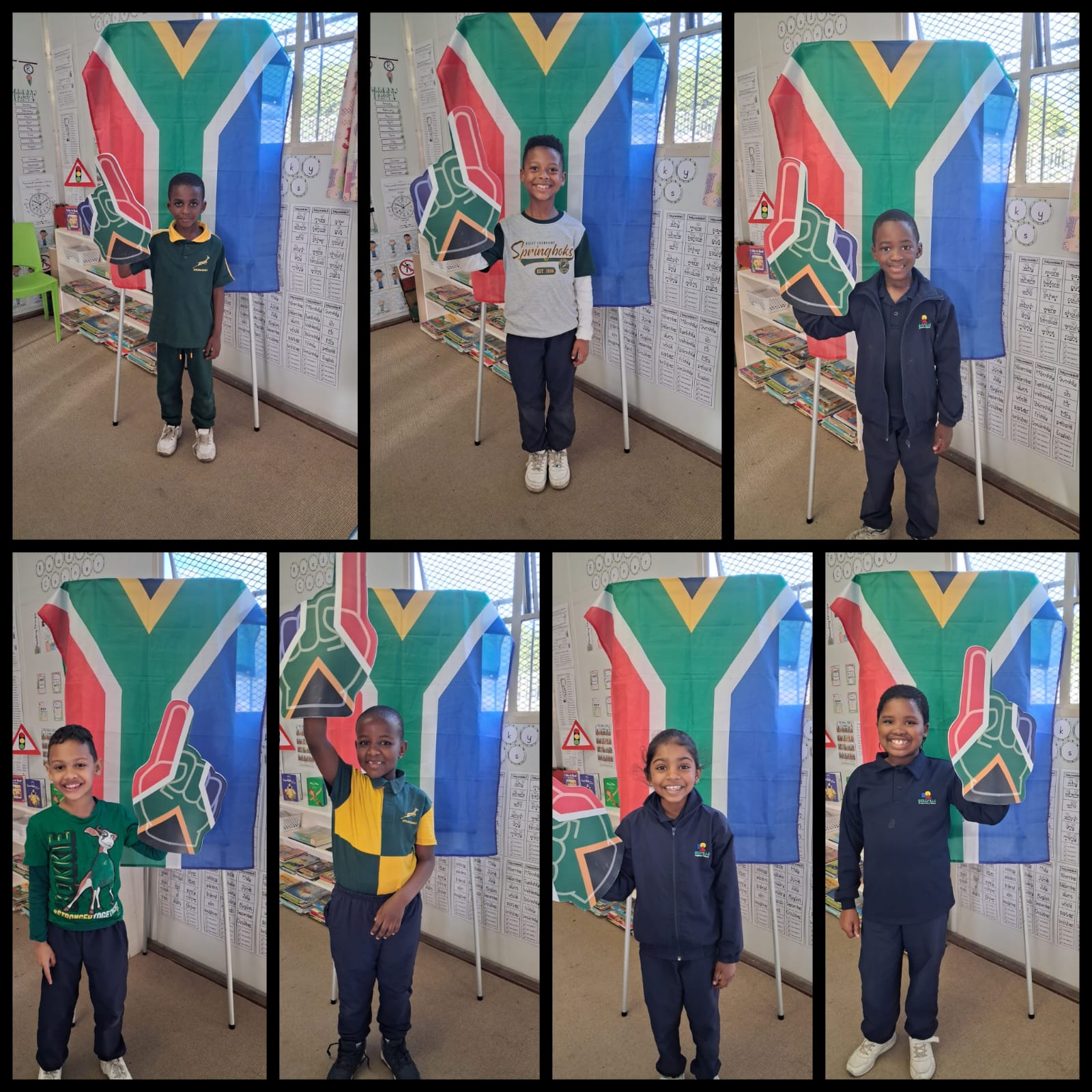 Eight children stand individually in front of a South African flag inside a classroom. Each child is dressed in various school uniforms and casual clothes. The background shows educational posters and a window with bars.